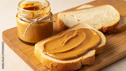 A jar of creamy peanut butter next to slices of bread, perfect for a delicious and easy snack.