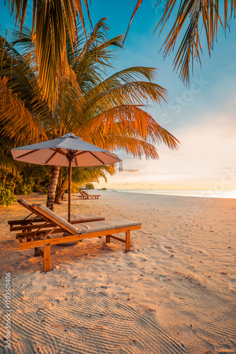 Fototapeta Naklejka Na Ścianę i Meble -  Love romantic sunset beach couple lounge chairs and umbrella at luxury tropical resort, calm ocean shore and serene seaside, perfect for summer vacation, honeymoon travel and exotic paradise getaway