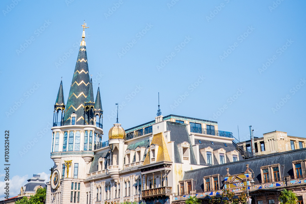 Fototapeta premium A stunning view of Batumi’s Astronomical Clock Tower and surrounding historic buildings in Georgia. The pointed spires, golden domes, and intricate European-style unique design of Georgian cultures