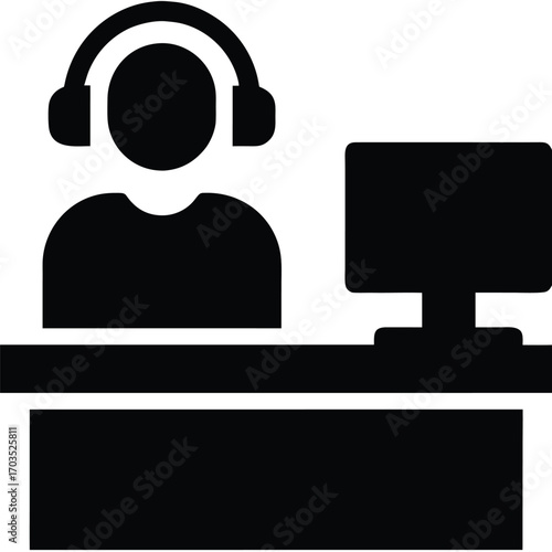 Simple black icon showcases a person with headset at computer desk in silhouette