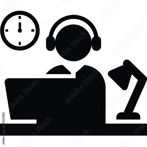 Silhouette of an individual wearing headphones and working diligently at a laptop with a desk lamp