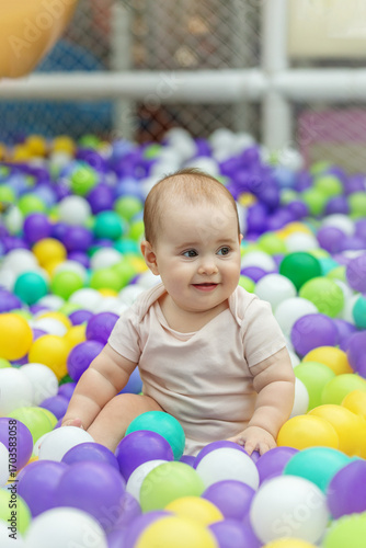 Smiling baby playing in colorful ball pit. Early development