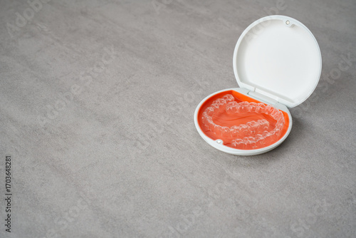 Orthodontic aligner and orange case placed on the table.　Dental orthodontic mouthpiece.