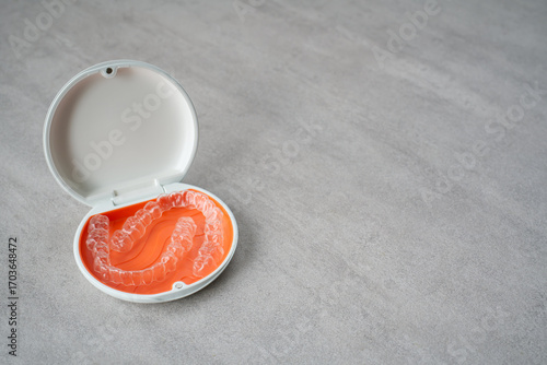 Orthodontic aligner and orange case placed on the table.　Dental orthodontic mouthpiece.