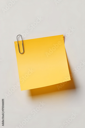 Empty yellow sticky note, held by a metal clip.
