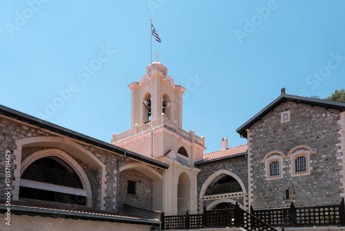 Greek flag above the bell tower of Holy Monastery of the Virgin Mary of Kykkos on sunny summer day. Cyprus.