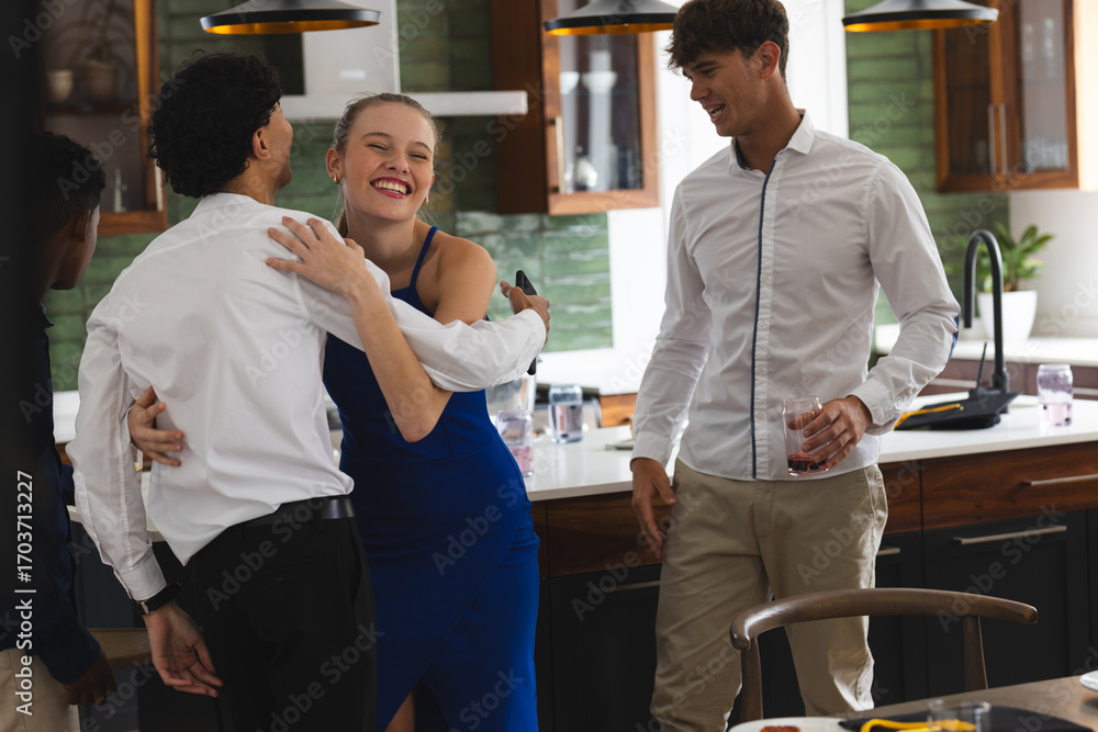 Obraz premium Teens celebrating at home, smiling and hugging in modern kitchen setting