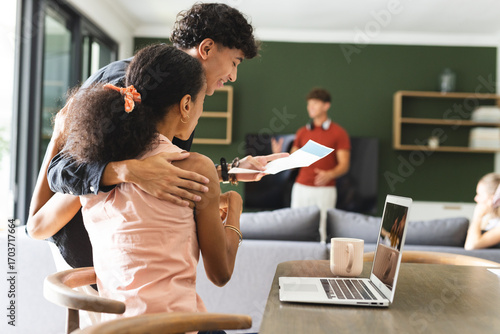 Teenagers celebrating success at home, smiling and looking at laptop together
