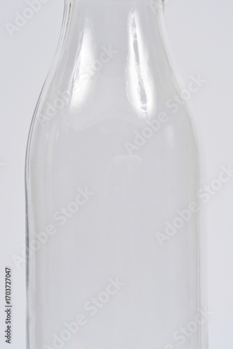 A macro shot of the neck and body of a clear glass bottle, showing the subtle reflections and textures on its smooth surface