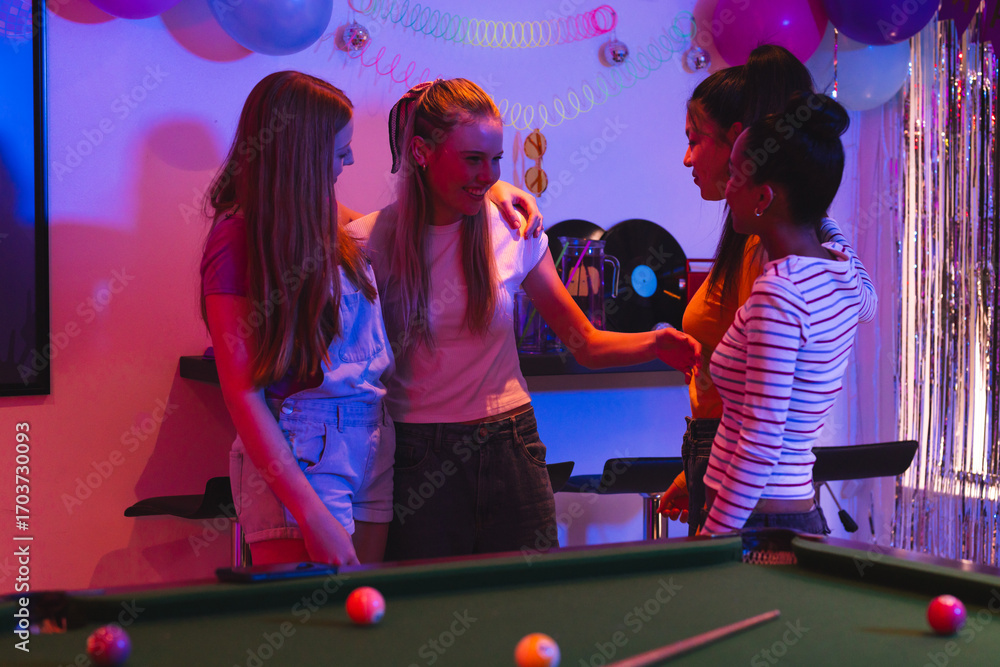 Naklejka premium Teen girls celebrating together around pool table, enjoying festive party atmosphere