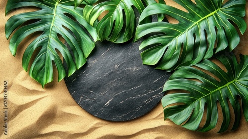 Dark round plate, tropical leaves on beige sand