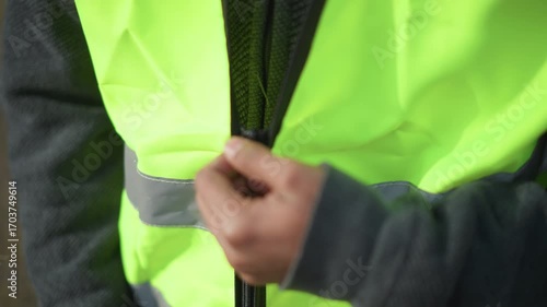 Close-up view of neon green reflective safety vest with partially open zipper, featuring bright high-visibility fabric and horizontal silver reflective stripes
