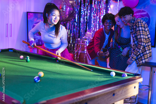 Teenagers playing pool at birthday party, enjoying celebration with friends