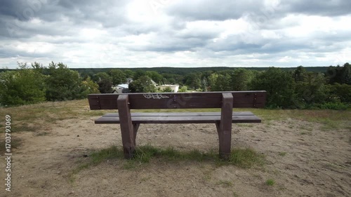 Time lapse video of a wooden park bench as sunlight shifts over the forested hills near Krähenberg in Caputh, Brandenburg.