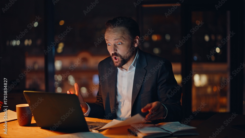 Fototapeta premium Emotional employee arguing virtual conference sitting dark office. Mad boss