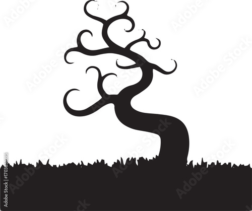 Silhouette of a twisted gnarled spooky tree with bare branches on a grassy field