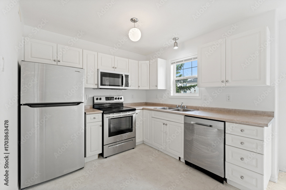 Fototapeta premium Clean and well-lit kitchen with stainless steel appliances and white cabinets