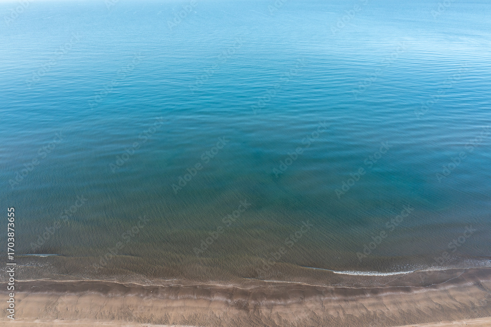 Obraz premium Tranquil blue sea and sandy shoreline