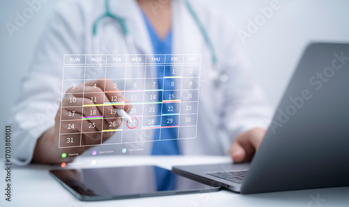 Doctor scheduling appointment on digital calendar using laptop and tablet, healthcare planning, telemedicine booking and innovation concept for online medical consultation and patient management