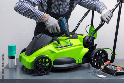 Lawnmower repair.  Technician in unifoprm  is repairing a electrical mower on workbench.