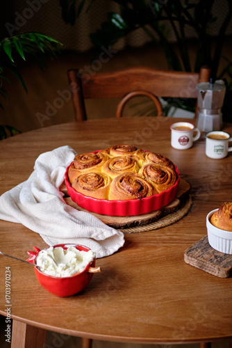 Cinnabon cinnamon rolls with pumpkin, nuts, caramel and mascarpone cream, covered with glaze. Rustic wooden table. Side view. Sweet homemade pastries, autumn pastries.