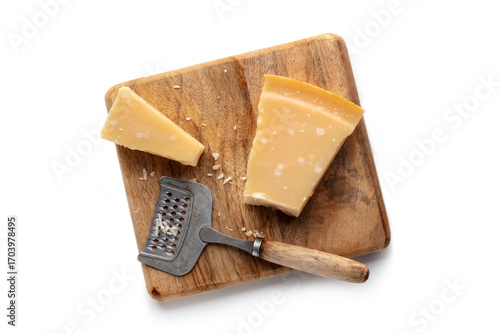 Parmesan cheese wedge on a wooden cutting board, with a cheese grater, isolated on a white background