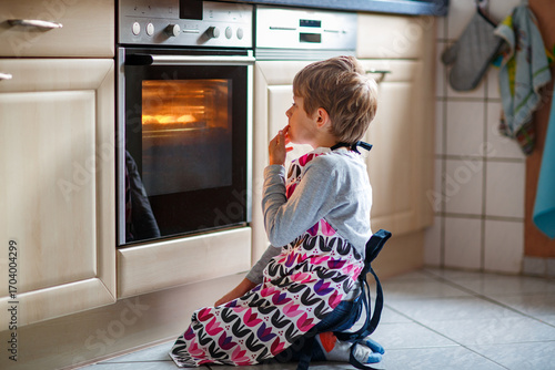 фотографія Cute blond boy baking muffins or pie in domestic kitchen