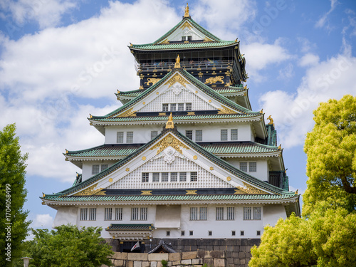 Osaka Castle, a famous historic landmark in Japan, with traditional Japanese architecture against a blue sky with clouds.
