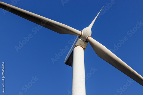 Close-up view of a modern wind turbine against clear blue sky. Renewable energy technology and sustainable electricity production concept.