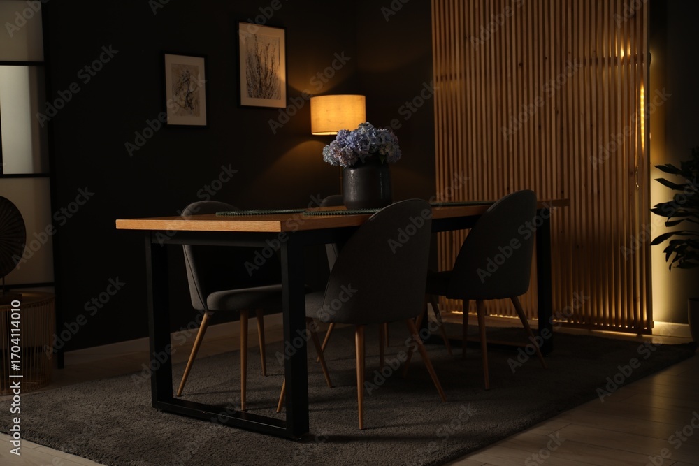 Fototapeta premium Wooden table with beautiful flowers and chairs in dining room at night