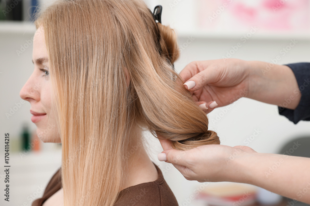 Naklejka premium Professional hairstylist working with client in salon, closeup