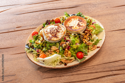 Warm melted goat cheese salad on an oak leaf lettuce bed, roasted cherry tomatoes, and crispy rye bread croutons