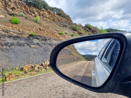 Conceptual image of travel, road seen from the car mirror