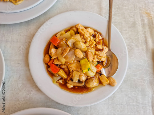 A plate of chicken with almonds on a white matte table