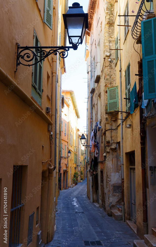 Fototapeta premium Narrow street in the historic center of the southern French city of Menton with stone houses and colorful facades