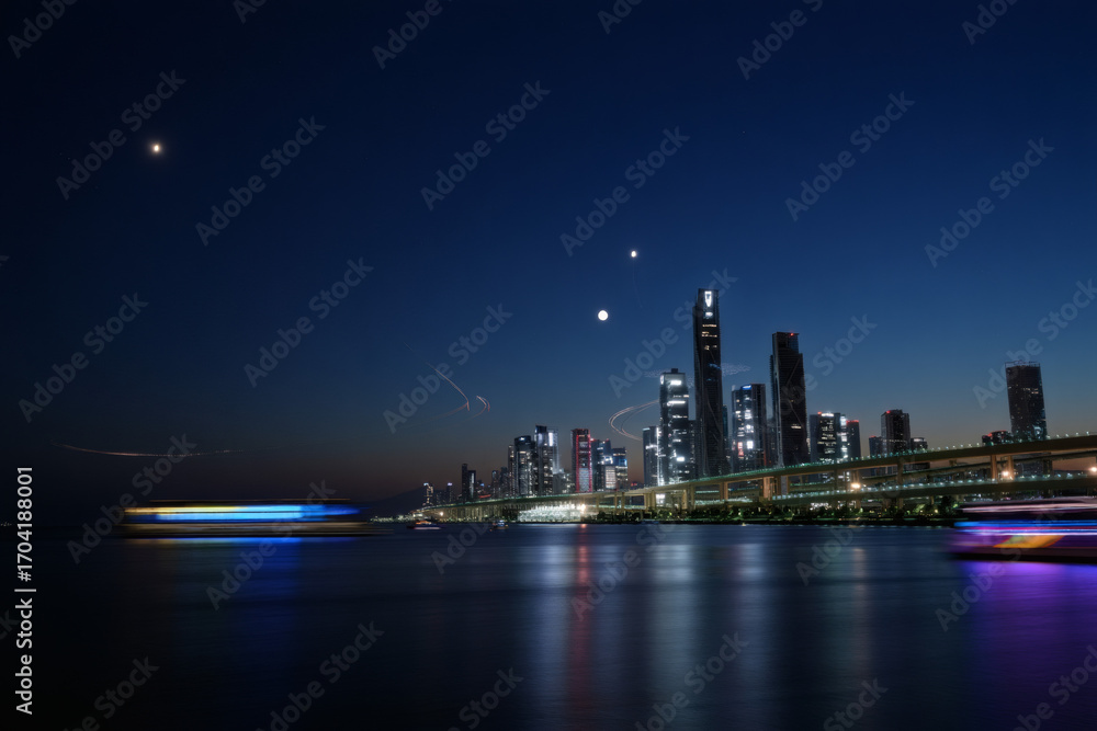 Naklejka premium Night cityscape of Hong Kong's downtown skyline with colorful skyscraper lights reflecting on the water