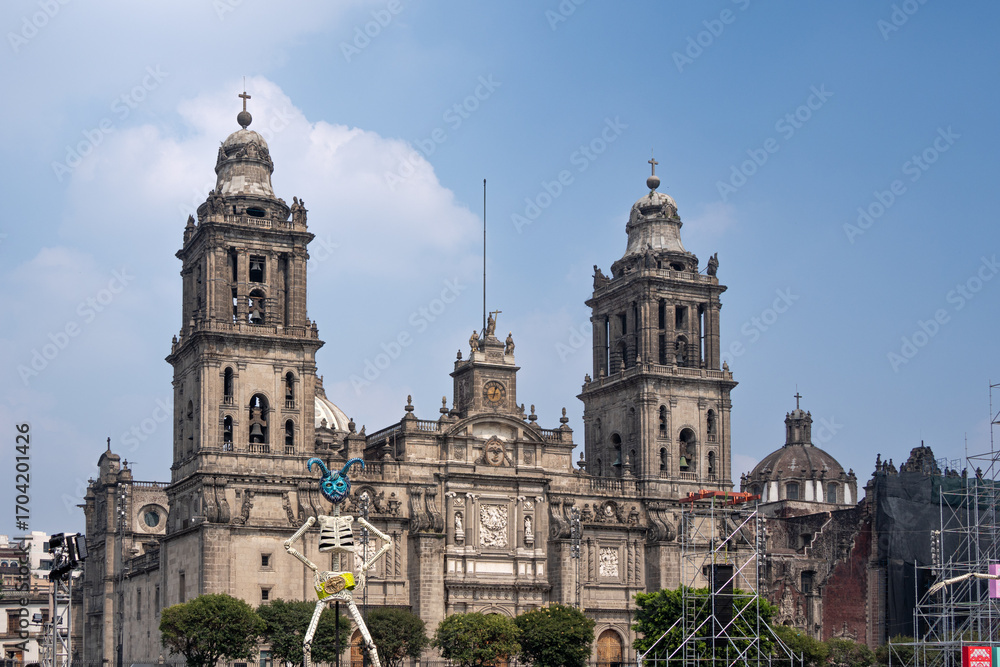 Obraz premium The two tall buildings are very old and have a lot of detail on them. The sky is clear and blue. Day of the Dead celebration in Mexico, papel picado crafts, offerings, La Catrina