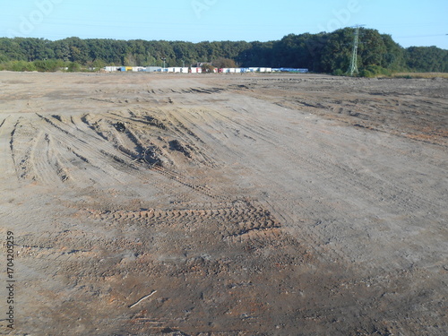 Flat terrain, newly leveled. Trees in the background.