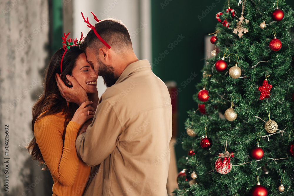 Fototapeta premium Happy couple embracing near christmas tree at home