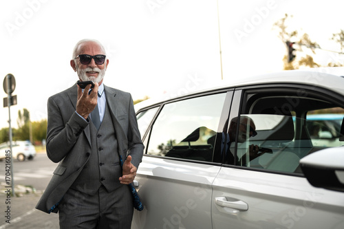 Wallpaper Mural Senior businessman talking on smartphone near car Torontodigital.ca