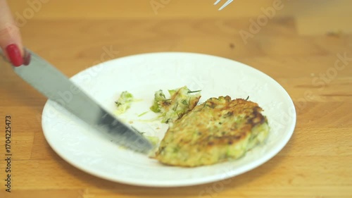 Fork is on a plate with a piece of food on it. The fork is being used to cut the food