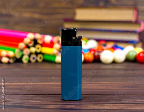 Blue lighter on wooden table with pencils and colorful balls
