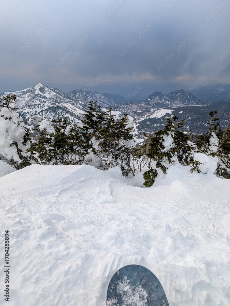 Fototapeta premium Snowboarder's point of view from a snowy slope at Shiga Kogen ski resort in Japan.
