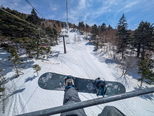 Valokuva First person view of a snowboarder riding a chairlift up a snowy mountain in Japan