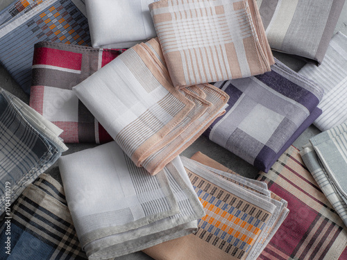 A diverse collection of neatly folded men's handkerchiefs with a variety of classic patterns and colors is shown in a close-up, top-down view.
