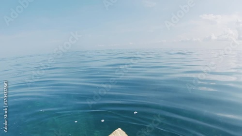 Surfer sitting on surfboard in ocean, first person view, panorama of surfing spot