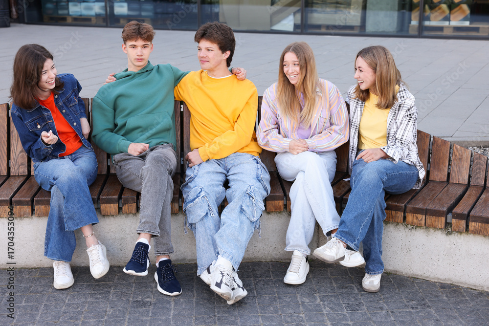 Obraz premium Group of teenagers sitting on bench outdoors