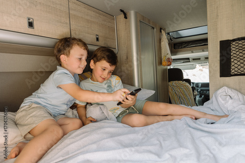 Two brothers playing games on smartphone inside camper van during road trip