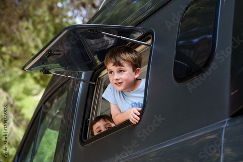 Children looking out of camper van window enjoying road trip