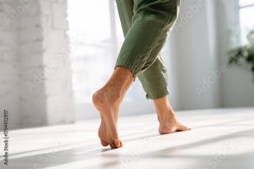 Close up focus on young female feet walking barefoot on clean tile floor at home. Young woman standing on warm floor indoors, underfloor heating concept. Woman's legs in bathroom. Floor heating
